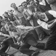A crowd of people watching a tug of war match during the opening of a new sports ground at Elstree, 1949.